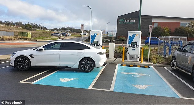 A photo of a white BYD (pictured) shows the car plugged into a charging station in the coastal suburb of Howrah in Hobart