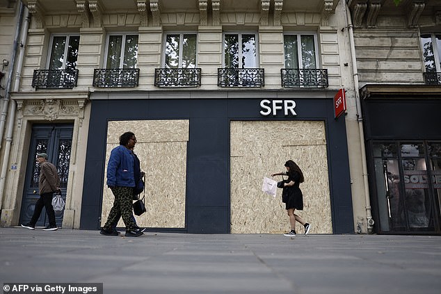 Pedestrians walk past a store of French telecommunications and mobile network company SFR (file image)