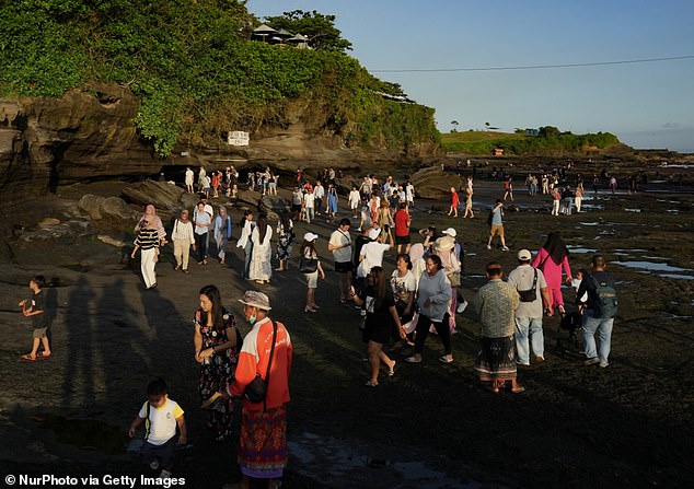 Bali's tourism minister wants tourists to spread out more across the island, but doesn't want locals to protest against visitors (pictured are tourists visiting Bali's Pura Batu temple)