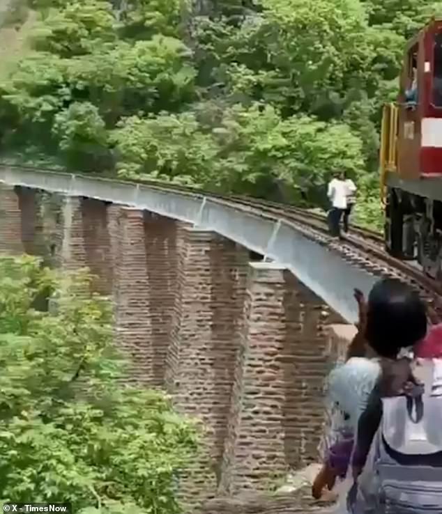 A couple were seriously injured after jumping from a railway bridge into a 90-foot-deep gorge to escape an oncoming train during a photo shoot