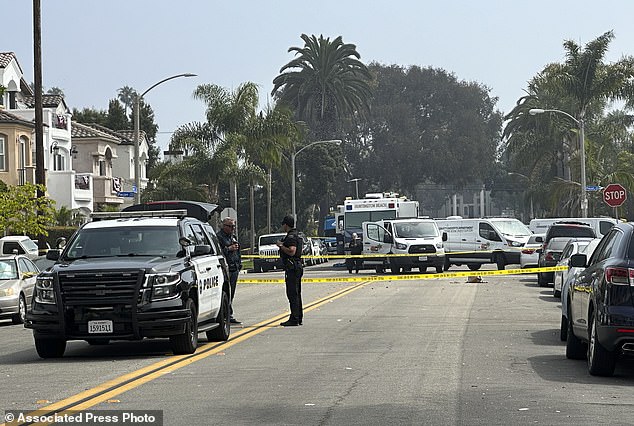 Police officers stand guard at the scene where police say several people were killed and injured in Huntington Beach