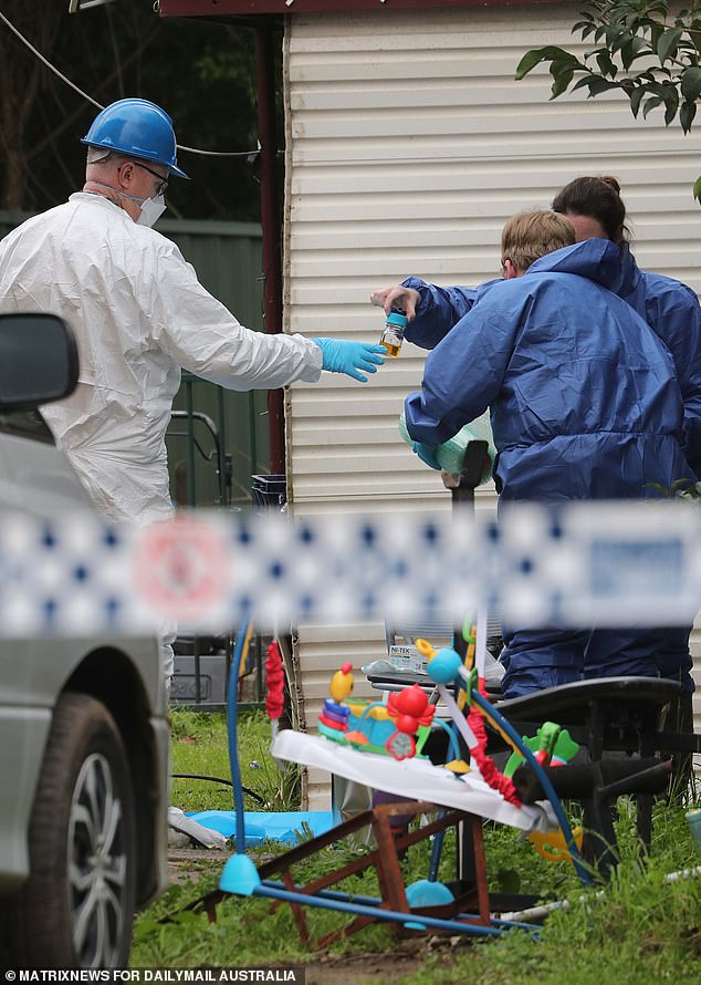 Pictured: Forensic personnel hold a second bottle of the tea-colored liquid during an investigation into the cause of the fire.