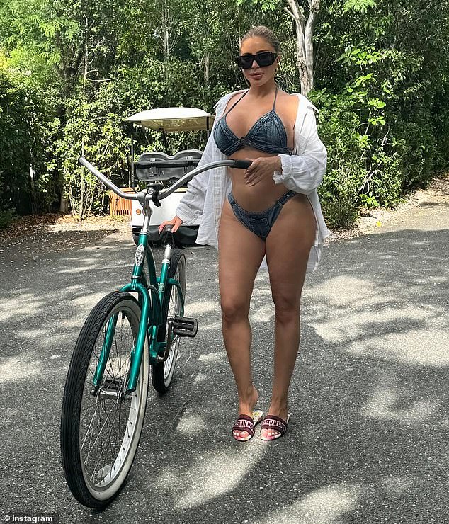 Larsa Pippen stood next to a bicycle, wearing a denim bikini, white button-down shirt and Christian Dior sandals, ahead of her 50th birthday on July 6