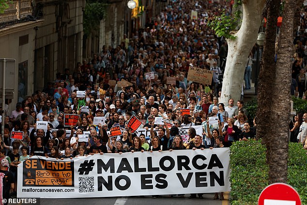 People hold a banner reading 'Mallorca is not for sale' as they take part in a protest against mass tourism and gentrification on the island ahead of the summer season in Palma de Mallorca in May