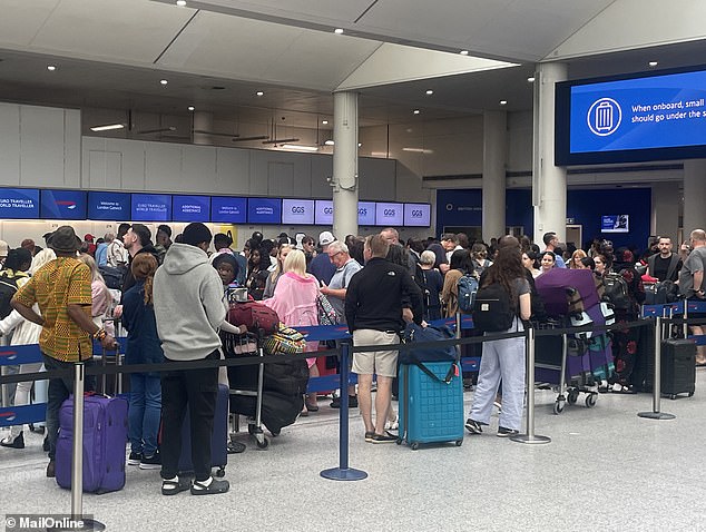 Passengers queue at check-in desks for British Airways flights at London Gatwick this morning