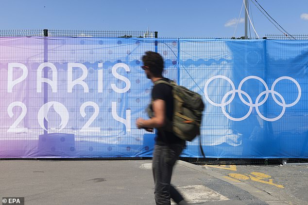 A man walks past a sign with the Paris 2024 logo in Paris, France, July 17, 2024