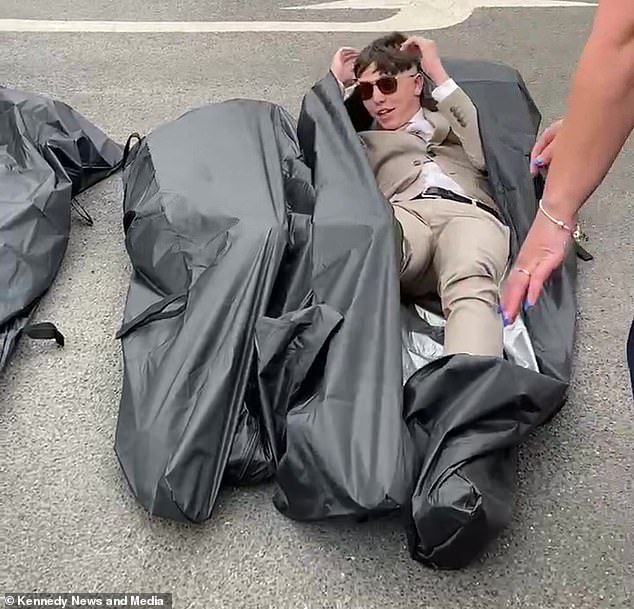 Lucas Jameson, 16, from Oswaldtwistle in Lancashire, made a grand entrance at his Year 11 prom dressed in a black body bag (Lucas is pictured emerging from a body bag)