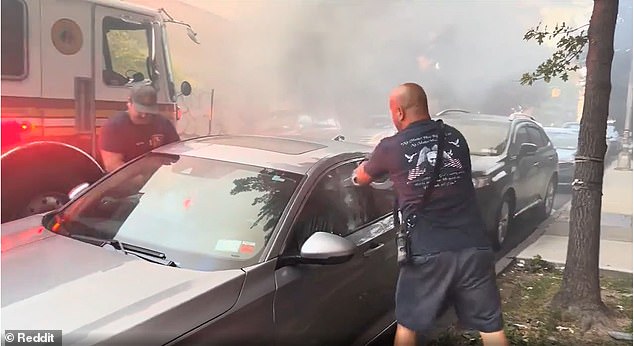 A firefighter uses a large medallion to hit the passenger side window of the Honda before moving to the driver's side