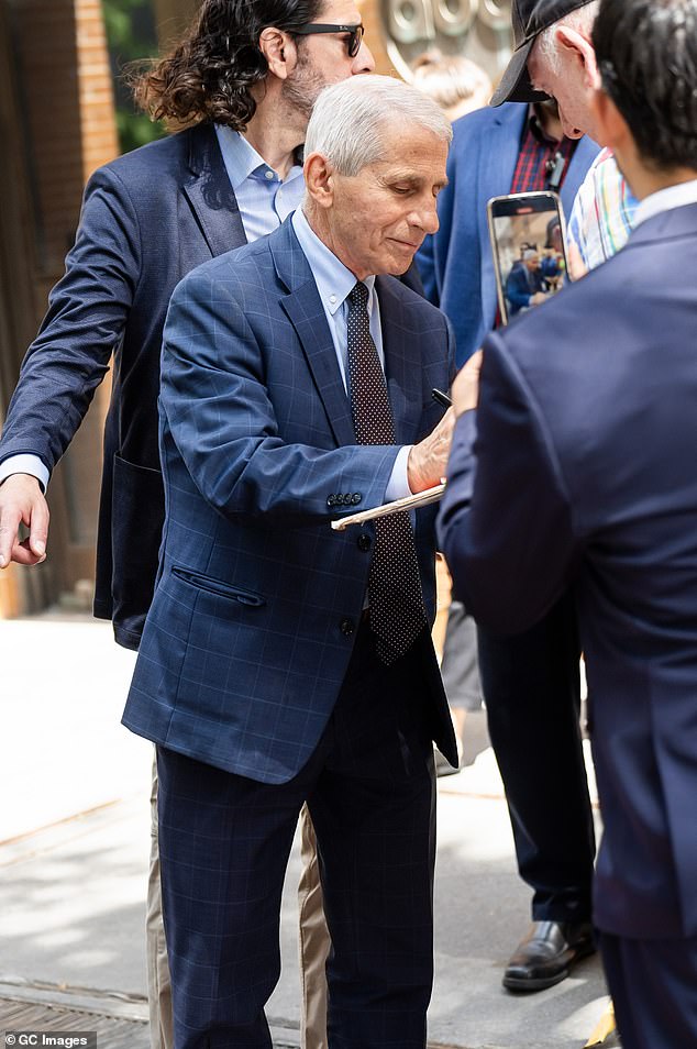 Fauci signs autographs outside ABC studios in New York with a member of his US Marshals team behind him