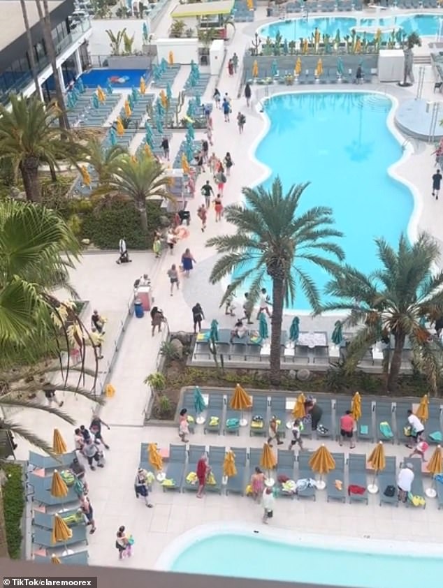 Dozens of holidaymakers with towels in their hands rush to the sunbeds after patiently waiting for the gates to open at 8am at the popular Spring Hotel in Tenerife.