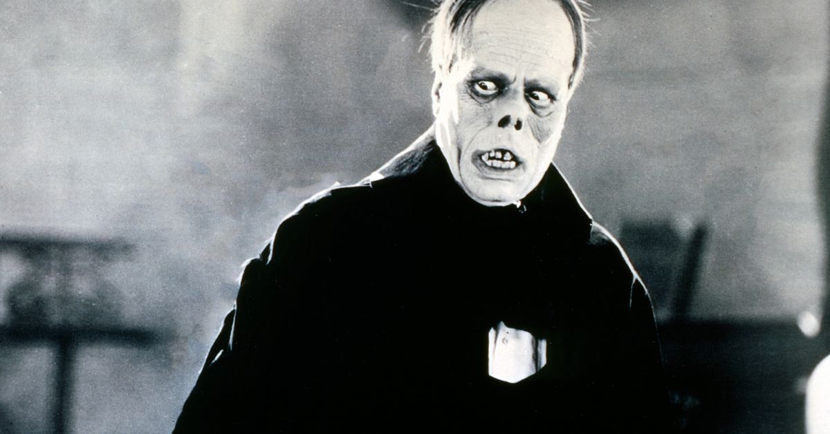 Lon Chaney as the Phantom in 1925's The Phantom of the Opera: a monstrous figure with a piggish, upturned nose, drawn-back lips exposing bare teeth, huge puffy bags under sunken eyes, and a small cap of hair on a very high forehead