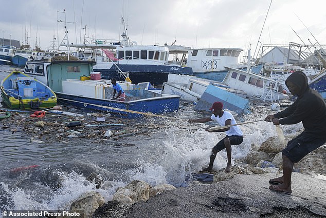 Fishermen pull a boat damaged by Hurricane Beryl back to the jetty at Bridgetown Fisheries in Barbados
