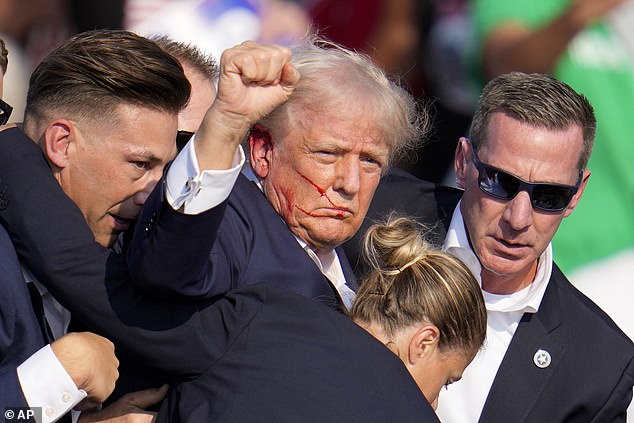 Trump holds a scoop with blood on his face as members of his U.S. Secret Service security team drag him off the stage at his rally in Butler, Pennsylvania on Saturday following an assassination attempt