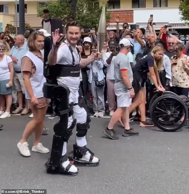 Kevin Piette, 36, who lost his legs in an accident at the age of 11, is filmed walking through the streets of Paris with the Olympic torch in his hands