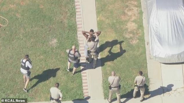 A man is surrounded by officers as he is arrested. Police reportedly began a high-speed chase with two of the suspects
