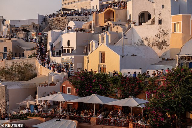 Shocking images from the picturesque island show crowds of tourists queuing on narrow walkways past white buildings with the famous sea-blue domes for the most beautiful holiday photos