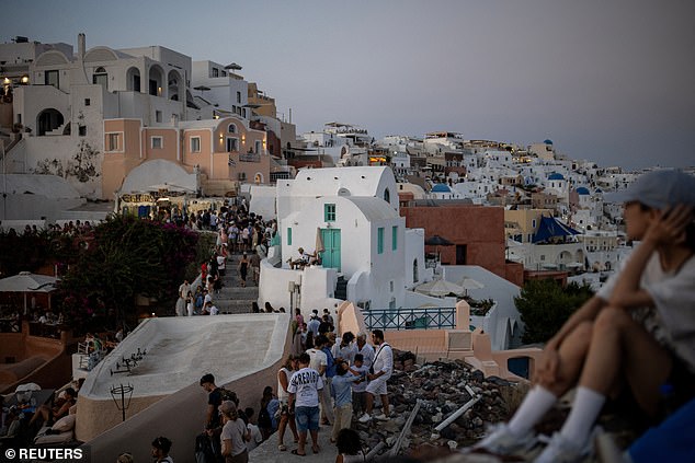 Tourists leave after watching the sunset in Santorini from Oia Castle, Santorini, Greece