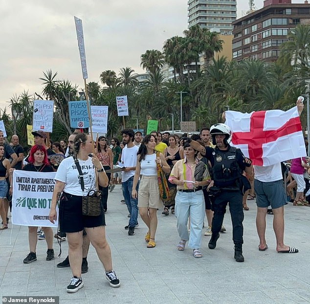 An England supporter stands among the crowd at the tourist office as protesters look on