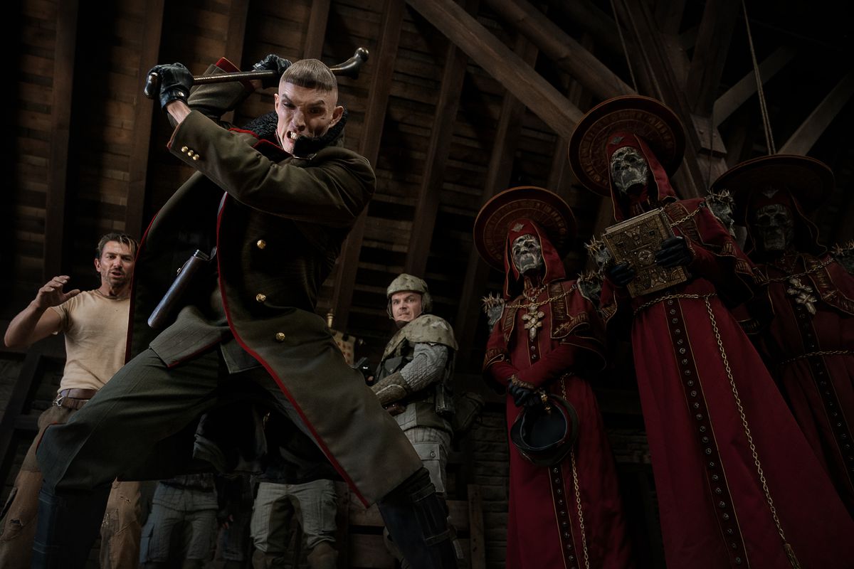 Admiral Noble (Ed Skrein) in the middle of the party, with his priests behind him