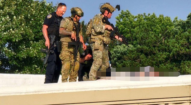 Police officers stand over Crooks' body on the roof of America Glass Research, just a few hundred yards from where Trump spoke.