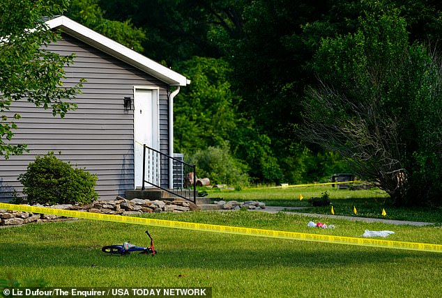 A child's bicycle, along with evidence markers, in the front yard of the Monroe Township home