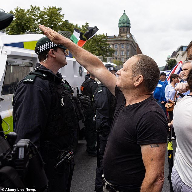 A man in Belfast appears to raise his hand in a Hitler salute to police officers during an anti-immigration protest