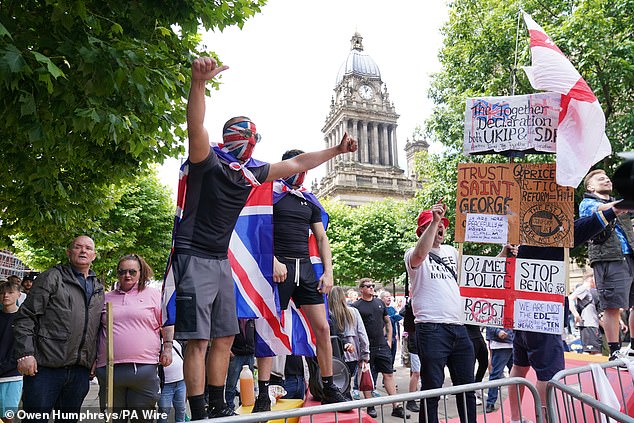 LEEDS: A masked protester raises his arms outside Leeds Town Hall. The protesters are believed to have been organised in response to the killings in Southport