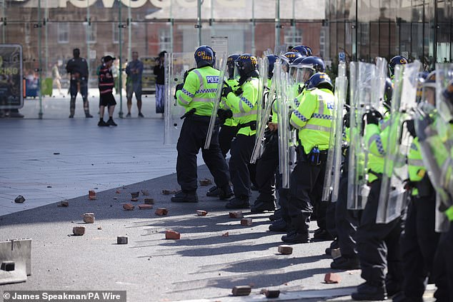 Rubble lies at the feet of police officers thrown by protesters in Liverpool amid horrific violence