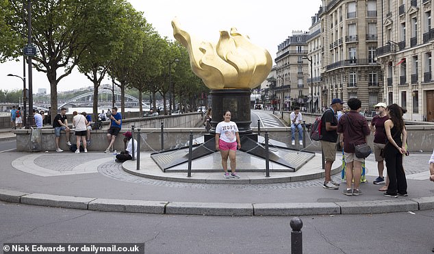 A woman poses at the Flame of Liberty, which has become the unofficial memorial to Diana