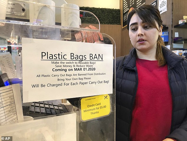 A cashier looks at a sign that reads "Ban on plastic bags" in a supermarket in New York on Wednesday, February 26, 2020. Starting March 1, 2020, many types of plastic bags will be banned in New York State in an effort to reduce pollution