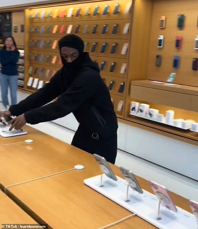 This is the insane moment a brazen thief casually snatches a batch of iPhones from the shelves of an Apple store in Oakland, amid Newsom's latest efforts to crack down on crime in the area.