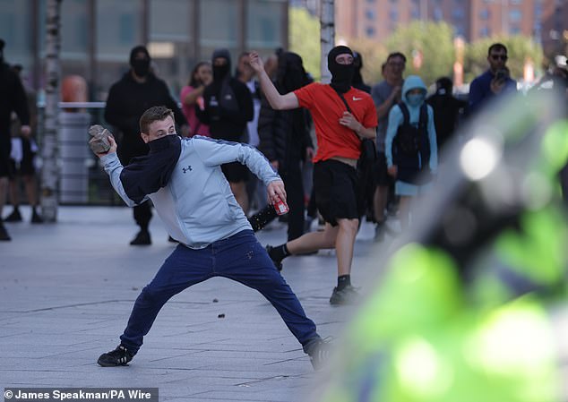 A man throws a brick during a protest in Liverpool. The violent unrest was sparked on Tuesday after misinformation spread on social media claiming that the teenager suspected of murdering three young girls was a radical Muslim migrant.