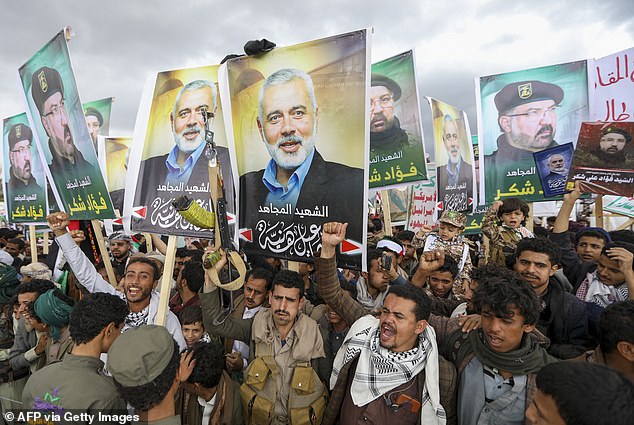 Yemenis wave flags and hold up placards of Hezbollah commander Fuad Shukr, who was killed in an Israeli strike, and Hamas leader Ismail Haniyeh, during a rally in the Houthi-controlled capital Sanaa on August 2, 2024