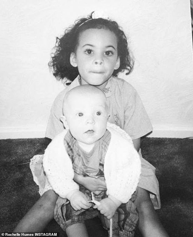 She grew up with her mother, stepfather and their daughter Emily, 29, in east London after her mother, Roz, and her Jamaican-born father split when she was a baby (pictured with Emily)