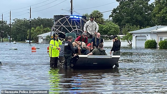 Police and emergency workers sail boats through once passable streets to rescue people from flooded homes