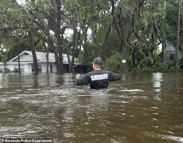 A member of the Sarasota Sheriff's Department is seen wading in water higher than his waist