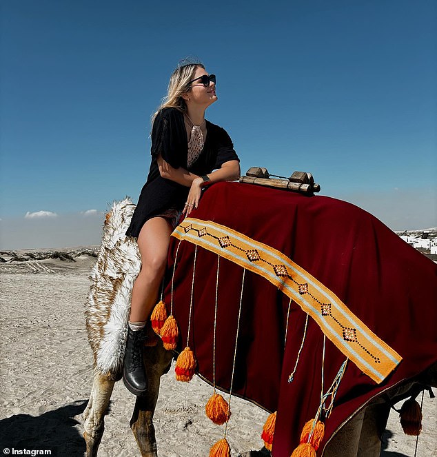 The glamorous swimmer rode a camel in the desert around Doha while wearing a loose, short black dress