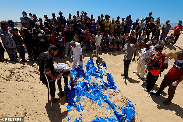 People watch as the bodies of unidentified Palestinians are buried in a mass grave after the bodies were handed over by Israel, amid the Israel-Hamas conflict, in Khan Younis, southern Gaza Strip, August 5, 2024