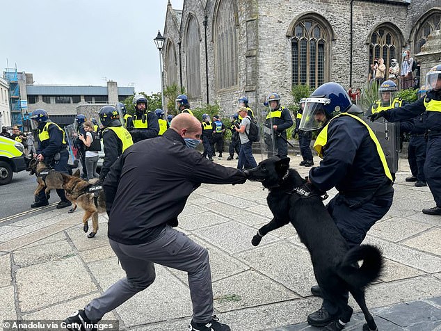 Police officers with dogs intervene after far-right protesters marched towards anti-racism campaigners and clashed with police in Guildhall Square in Plymouth