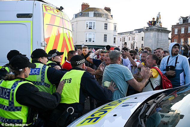 Police hold back anti-immigration protesters during confrontation on the seafront, on August 4, 2024 in Weymouth