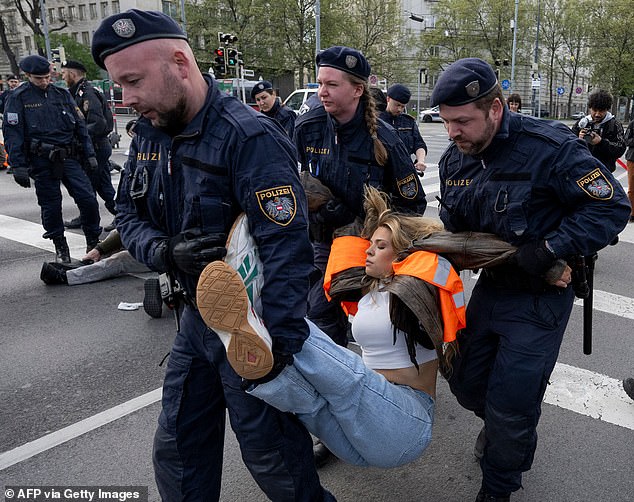 Austrian police officers take away German activist Anja Windl from the environmental movement Last Generation (Letzte Generation) after she blocked traffic with other activists at the Aspern Bridge on April 3, 2023 in Vienna