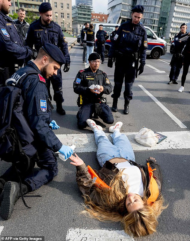 German activist Anja Windl of the environmental movement Last Generation (Letzte Generation) still lies on the ground after police officers freed her glued hand during her protest where she and other activists blocked traffic at the Aspern Bridge on April 3, 2023 in Vienna.