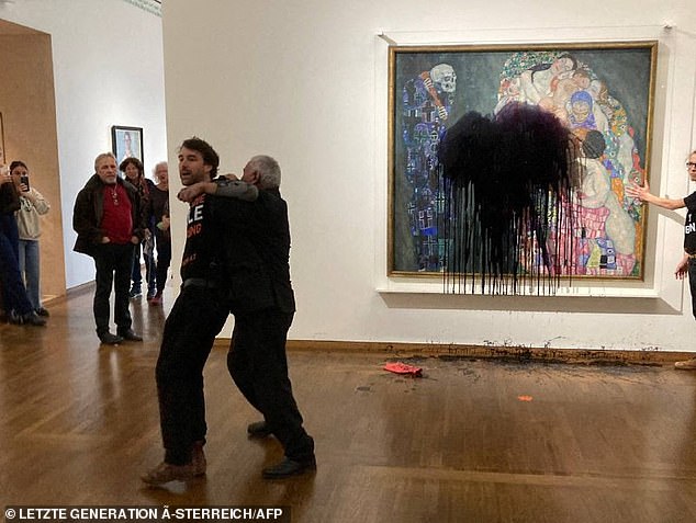 A security guard stops one of the climate activists after they threw paint on the famous masterpiece