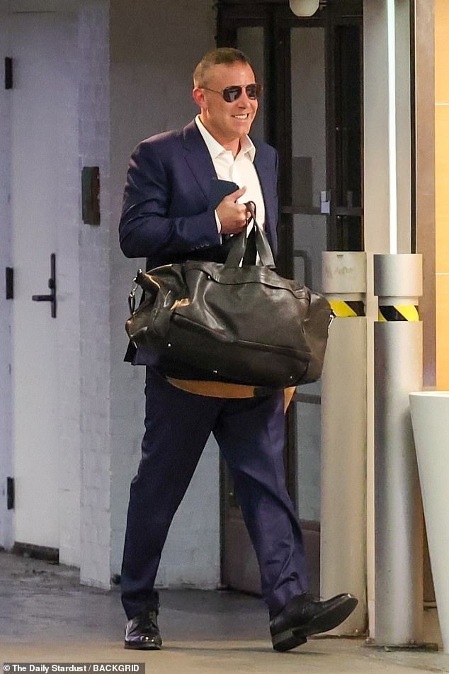 The actor, 51, was again without his wedding ring as he arrived at the office in a cheerful mood, dressed in a suit and with an iced coffee in his hand.