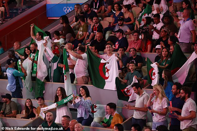 Algerian supporters jump to their feet as Imane Khelif enters the arena.