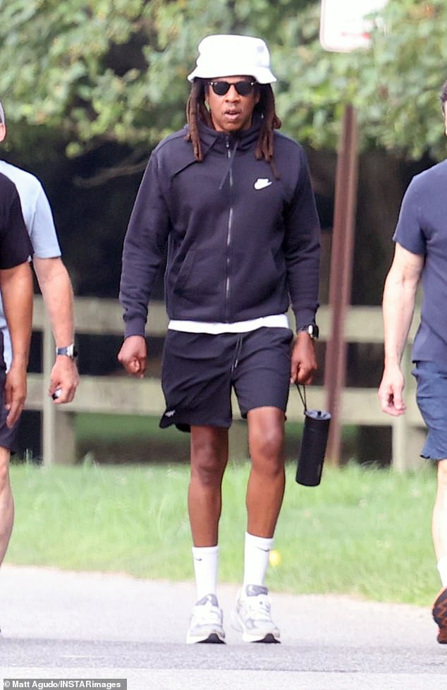 He wore a zip-up hoodie over a white tank top and black basketball shorts. He dressed for comfort, wearing high white socks and chunky gray sneakers.