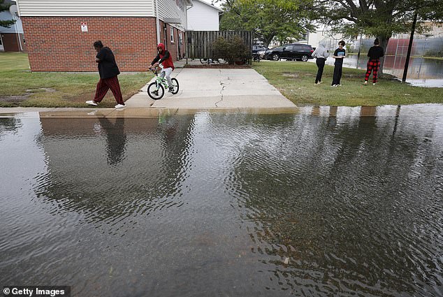 Neighbors survey flooded streets outside their apartments after two days of heavy rain from a tropical storm in Crisfield, Maryland