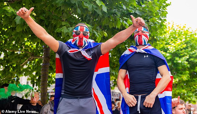 Two men hide their features with Union Jack masks, they hide the faces of cowards