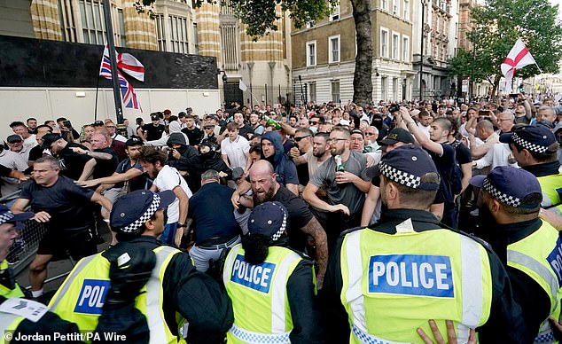 Nearly 6,000 public order officers have now been mobilised to respond to the riots, police sources told the BBC. Pictured: Police officers clash with protesters during the Enough is Enough protest in Whitehall, London