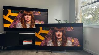 The LG G4 OLED TV on a TV stand, with the LG G3 OLED next to it on the floor, both showing the same scene from Bryce Dallas Howard in the movie Argylle